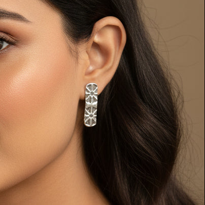 Light brown skinned woman with dark long hair wearing sterling silver stud earring with art deco design