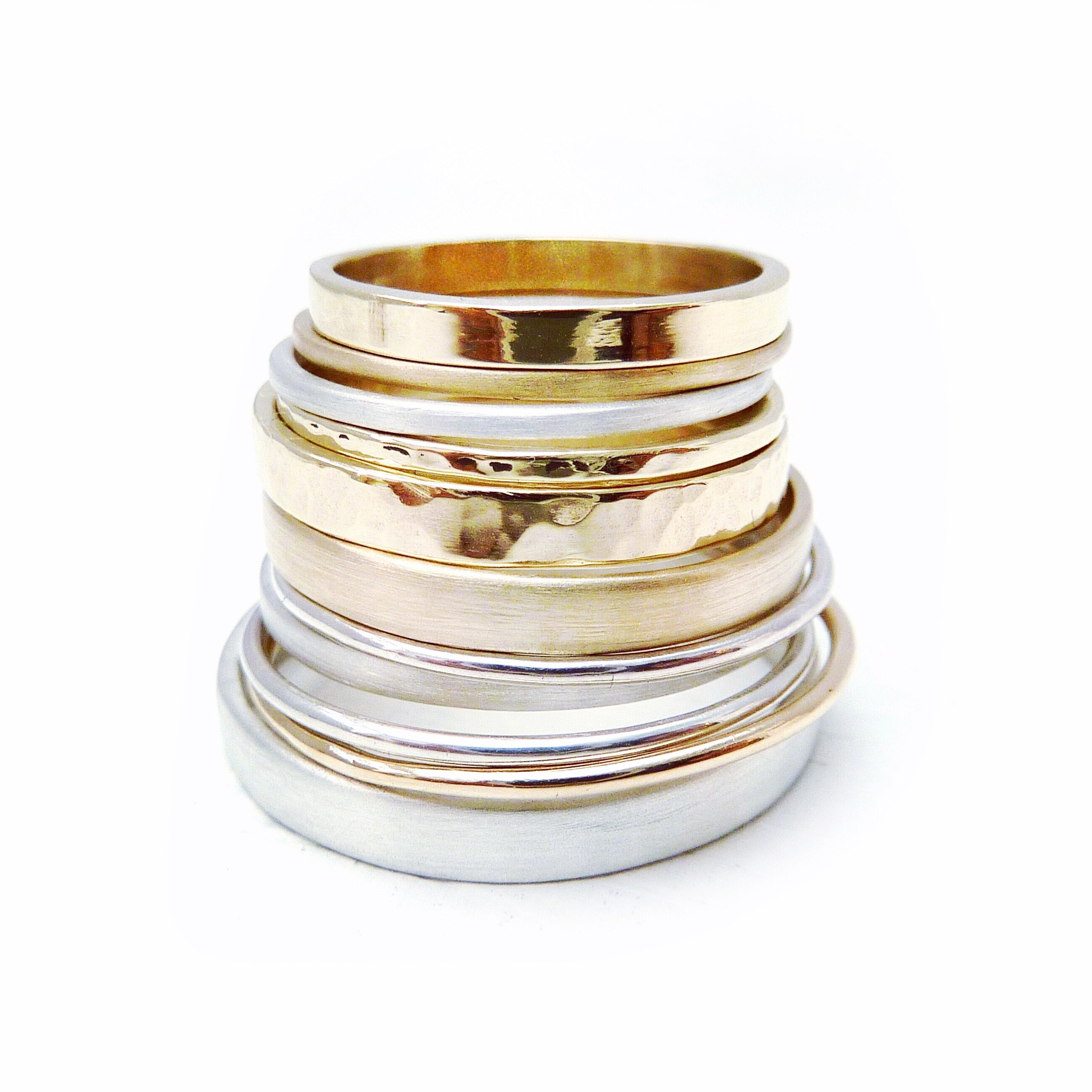 lots of solid sterling silver and solid gold wedding rings in a stack handmade sustainable in nottingham