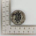 Circular metal jewellery impression die with decorative design next to a ruler on a white background sustainable Nottingham