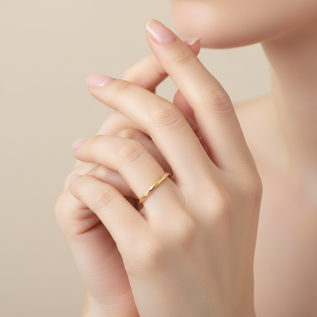 Hand wearing a solid gold skinny wedding ring with an unusual hammered design handmade by bottlebee in Nottingham who makes sustainable and bespoke jewellery