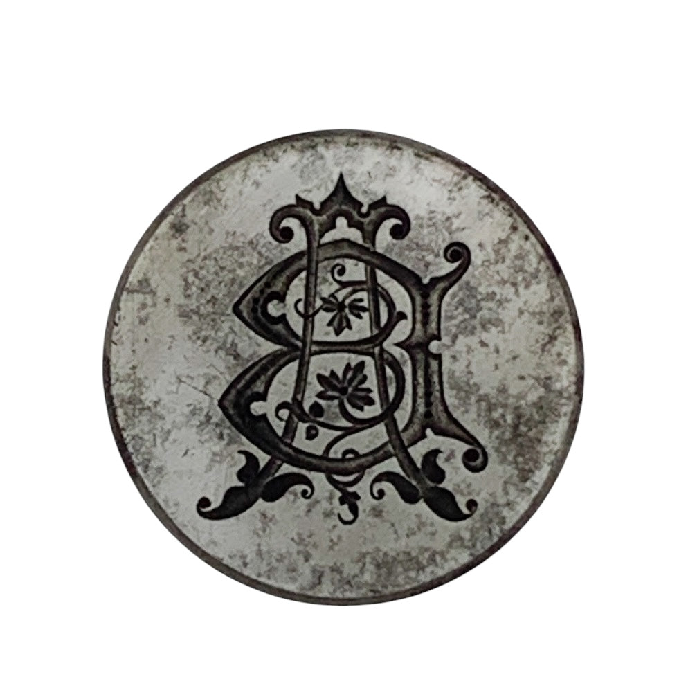 Decorative metal jewellery impression die with intricate black design on a white background