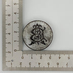 Decorative circular jewellery impression die with intricate design next to a ruler for scale on a white background made in Nottingham bespoke sustainable