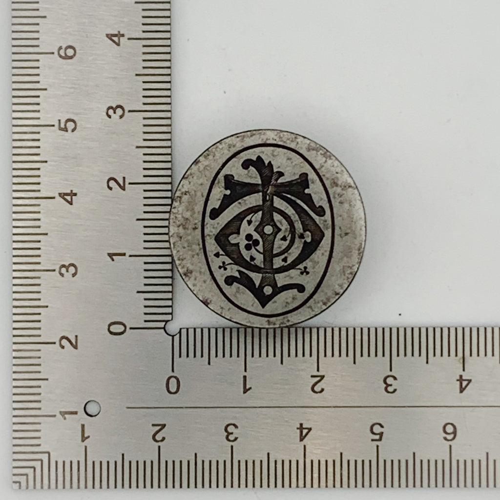 Decorative circular jewellery impression die with intricate design next to a ruler on a white background jewellery in Nottingham
