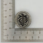 Decorative circular jewellery impression die with intricate design next to a ruler on a white background jewellery in Nottingham