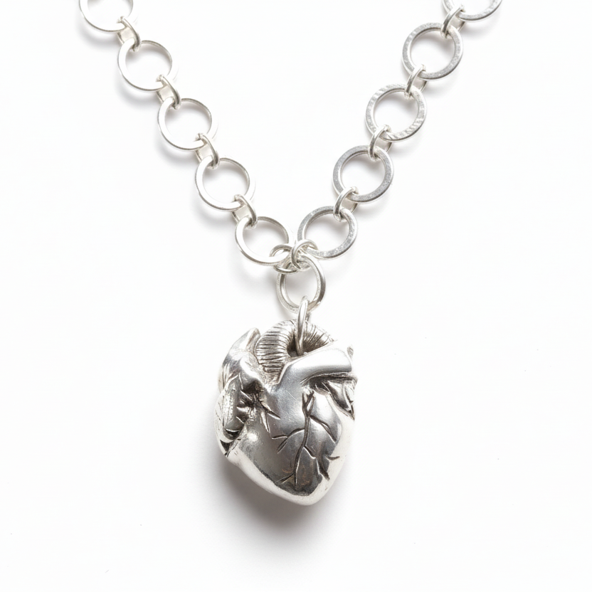 Handmade bespoke silver necklace with an anatomical heart shaped pendant on a white background