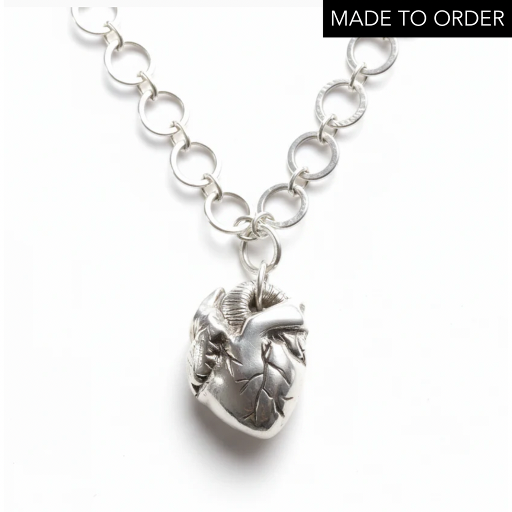 Silver chain necklace with an anatomical heart shaped pendant on a white background