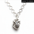 Silver chain necklace with an anatomical heart shaped pendant on a white background