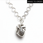Silver chain necklace with an anatomical heart shaped pendant on a white background