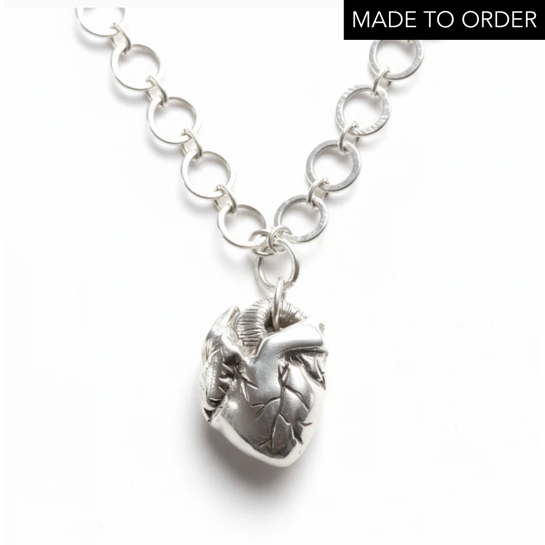 Silver chain necklace with an anatomical heart shaped pendant on a white background