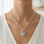 Silver handmade chain necklace with an anatomical heart pendant worn by a woman in a white top.