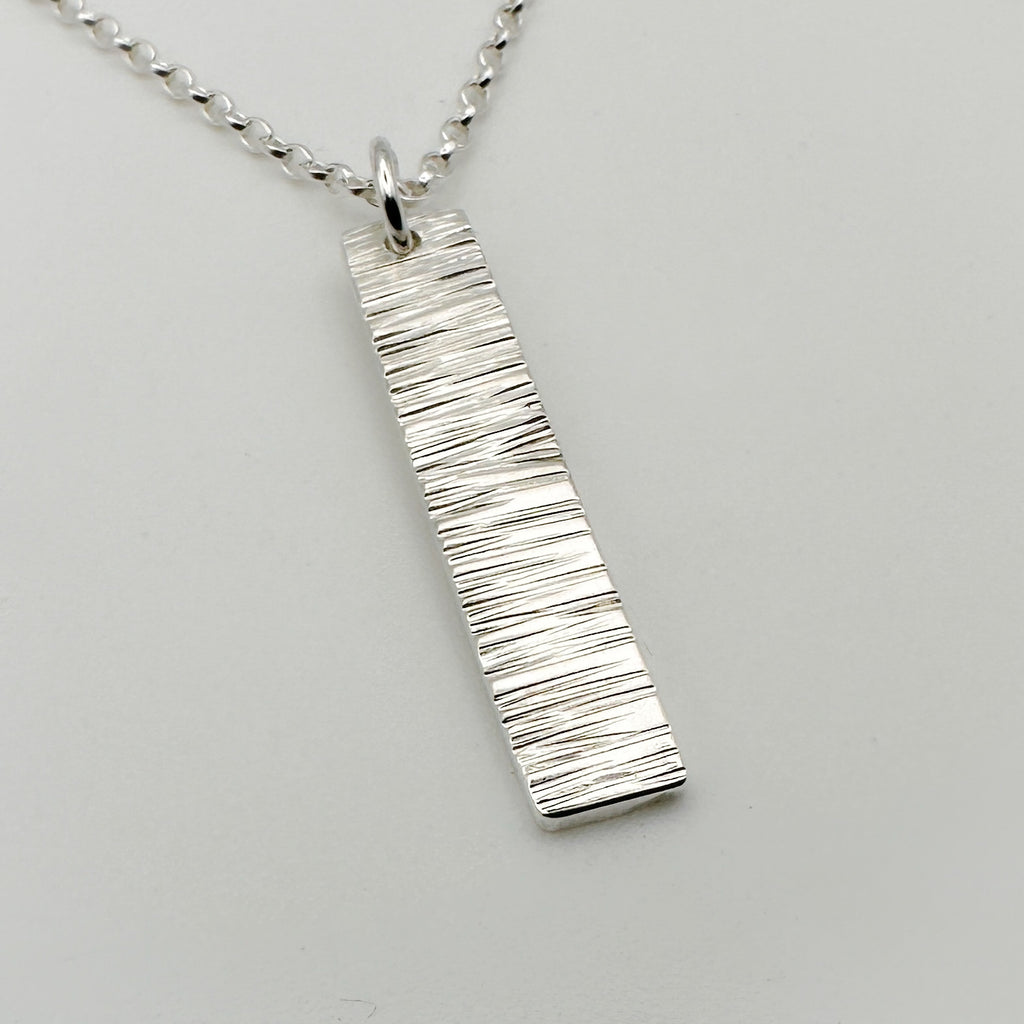 Sterling silver necklace with a bark textured pendant on a light grey background handmade jewellery by Bottlebee in Nottingham