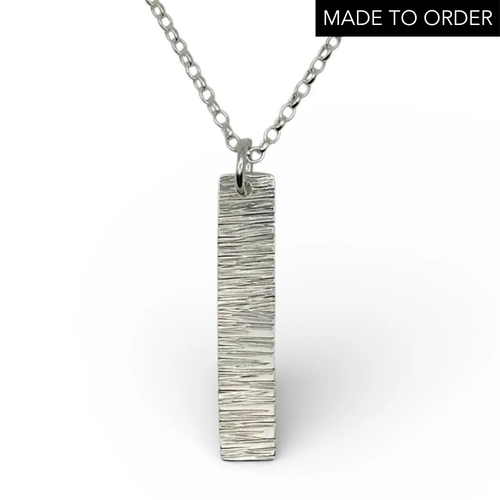 Bespoke handmade sterling silver necklace with a textured pendant like a hammered bark on a white background handmade jewellery by Bottlebee in Nottingham