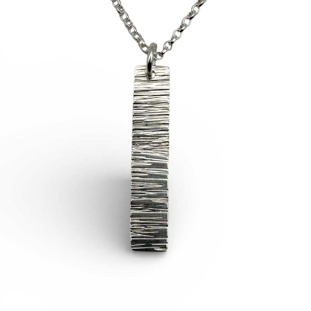 handmade solid silver necklace with a bark textured pendant on a white background