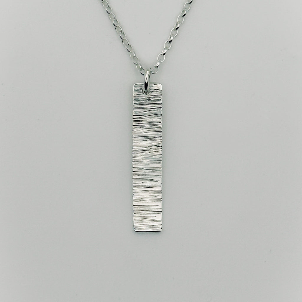 Silver pendant and belcher chain necklace on a grey background handmade by bottlebee who makes bespoke jewellery