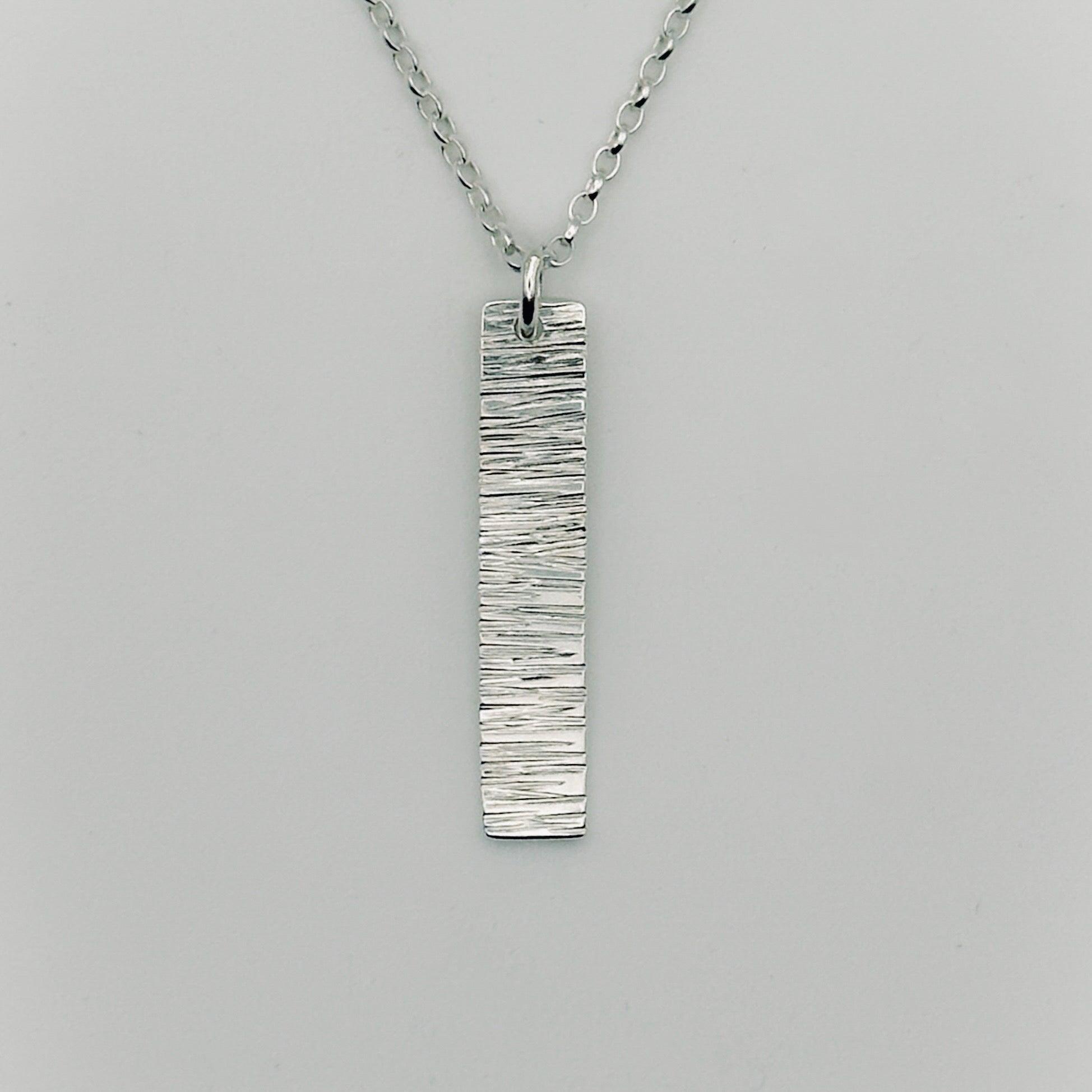 Silver pendant and belcher chain necklace on a grey background handmade by bottlebee who makes bespoke jewellery