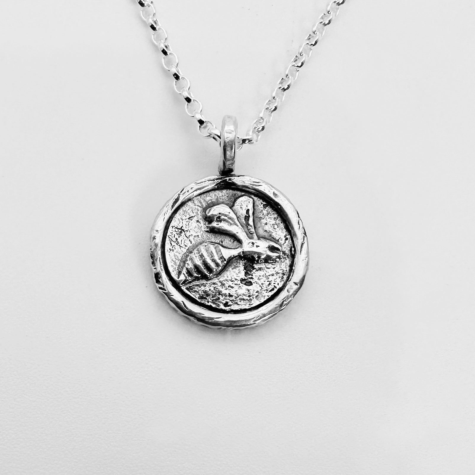 Silver bee pendant necklace with a raised bee surrounded by a silver enclosure handmade by bottlebee in nottingham who makes bespoke and sustainable jewellery