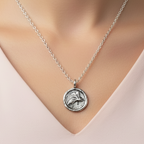 Silver necklace with a pendant on a mannequin wearing a light pink top.