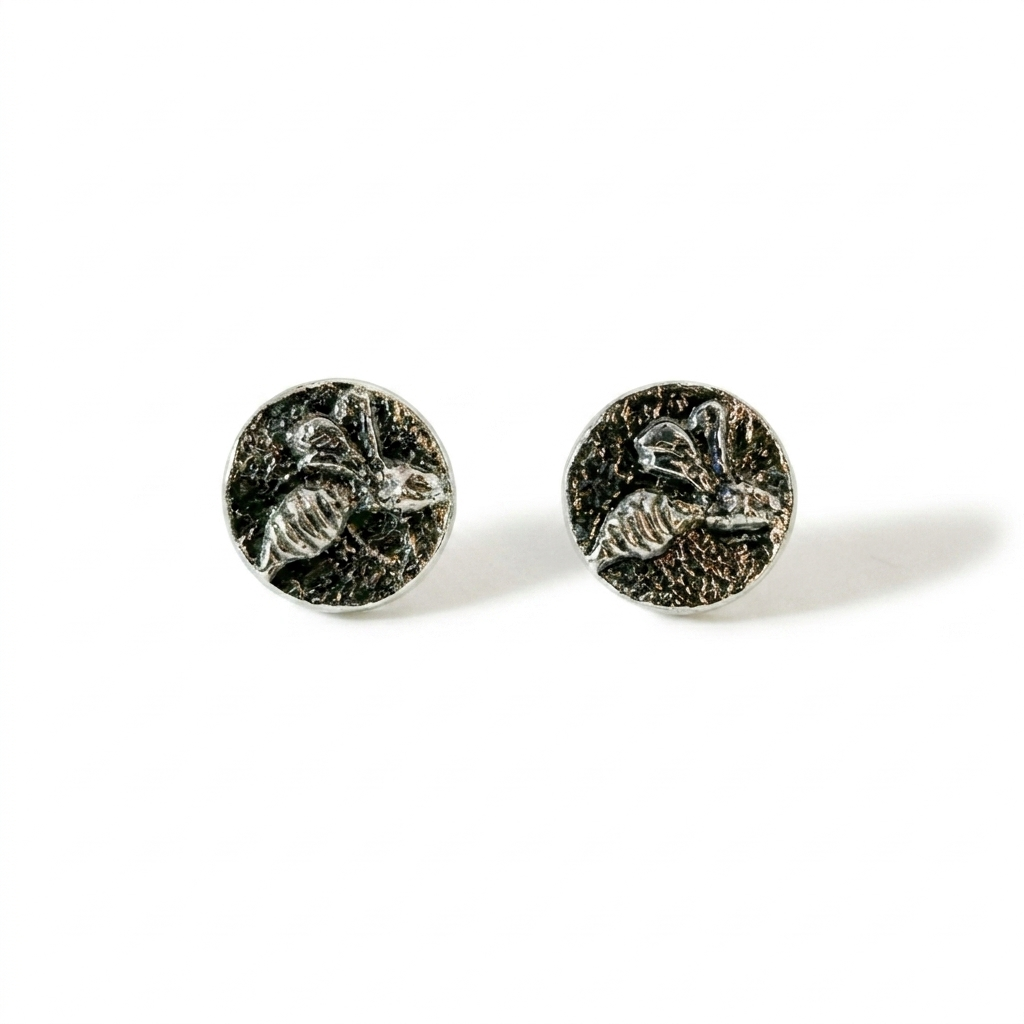 Pair of silver round earrings with bee design on a white background, handmade jewellery made by Bottlebee in Nottingham with sustainable and recycled silver
