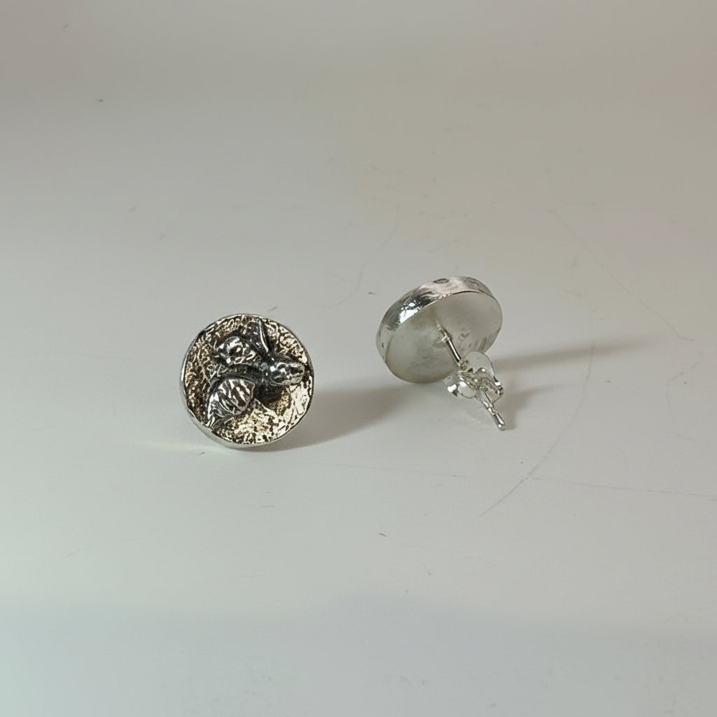 Small sterling silver round stud earrings with intricate and oxidised bee designs on a white surface handmade by Bottlebee who makes jewellery in Nottingham, commissions are welcome