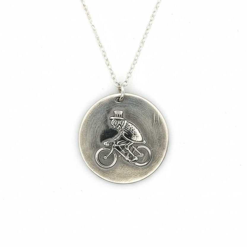 Silver necklace with a pendant featuring a flea riding a bike and wearing a top hat hamdmade by Bottlebee who makes sustainable bespoke jewellery in Nottingham on a white background