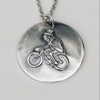 Silver necklace with a pendant featuring a flea riding a bicycle and wearing a top hat hamdmade by Bottlebee  who makes sustainable bespoke jewellery in Nottingham