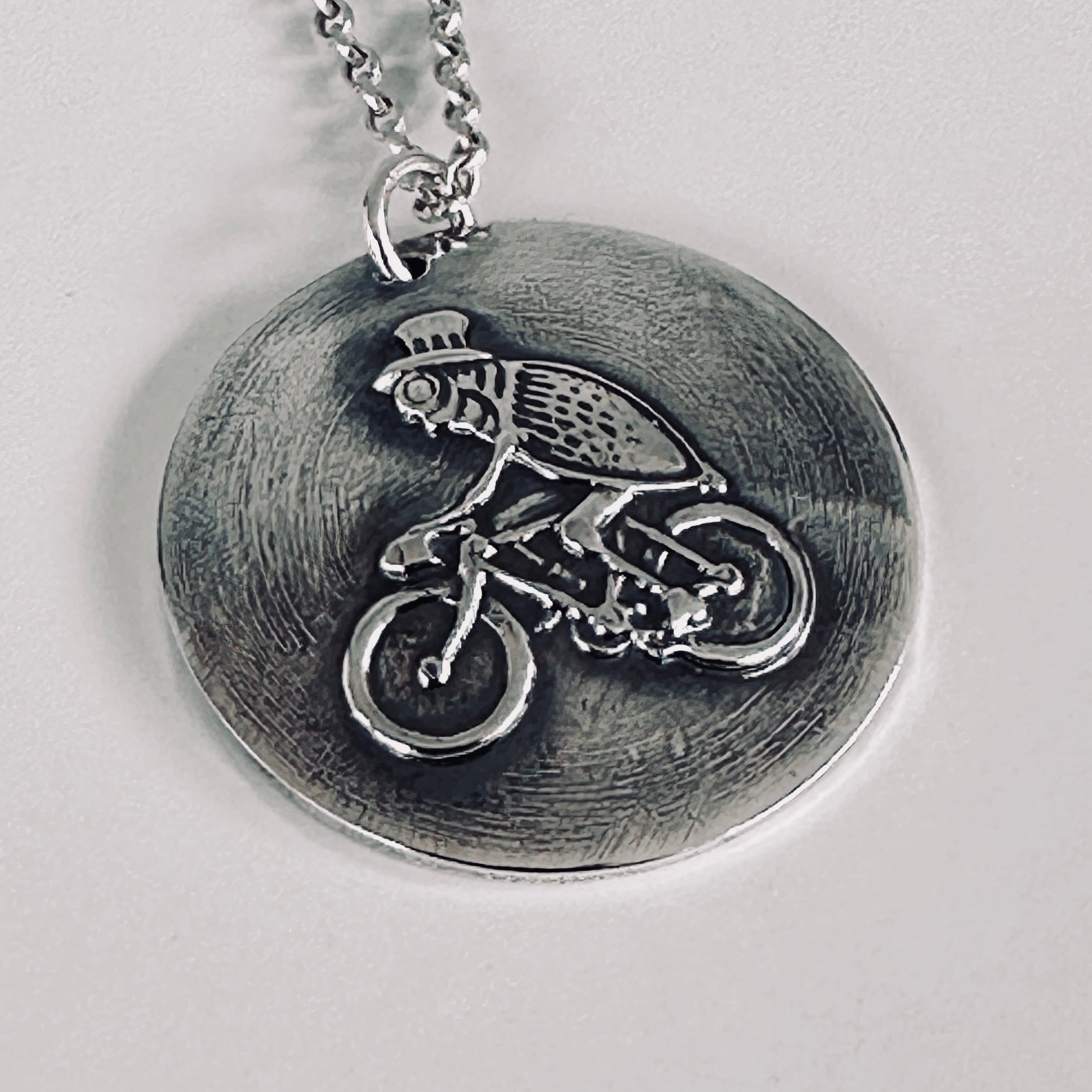 Sterling silver pendant with a flea on a bike wearing a top hat hamdmade by Bottlebee  who makes sustainable bespoke jewellery in Nottingham