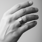 Mans hand wearing a silver art deco ring on a grey background,the wedding band is handmade by Bottlebee who makes sustainable bespoke jewellery in Nottingham