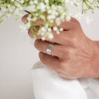 Woman holding a bunch of flowers on wedding day wearing sterling silver art deco wedding ring, the wedding band is handmade by Bottlebee who makes sustainable bespoke jewellery in Nottingham