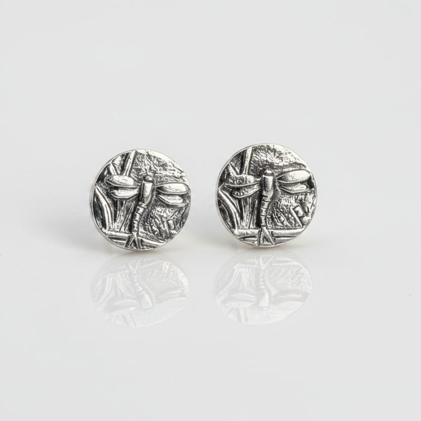Small sterling silver round stud earrings with intricate and oxidised dragonfly designs on a white surface handmade by Bottlebee who makes jewellery in Nottingham, commissions are welcome