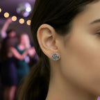 Close-up of a woman wearing a silver stud earring with an oxidised dragonfly and background of people and lights.