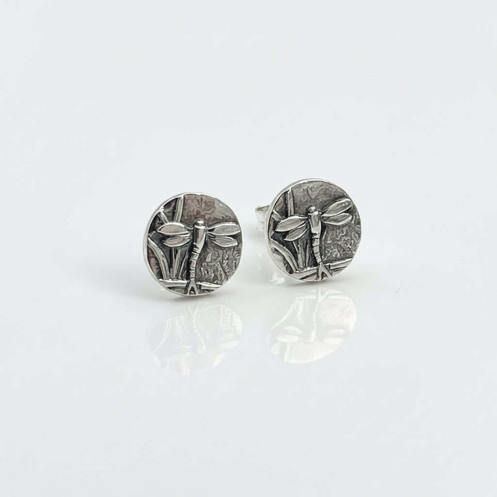 Small sterling silver round stud earrings with intricate and oxidised dragonfly designs on a white surface handmade by Bottlebee who makes jewellery in Nottingham, commissions are welcome