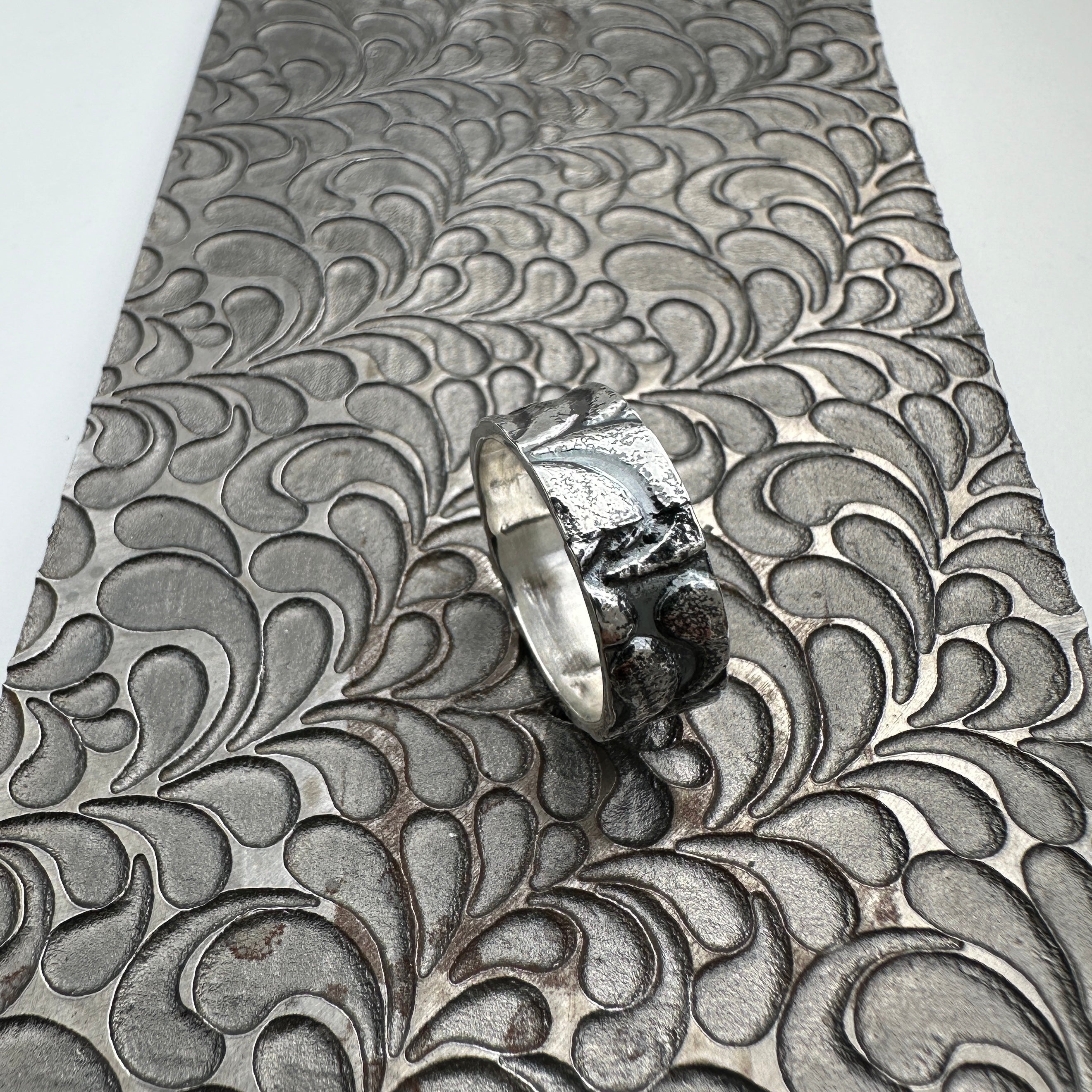 925 silver wedding ring band for a man woman or unisex with textured surface on a pattern plate used to make the design handmade sustainable bespoke jewellery Nottingham