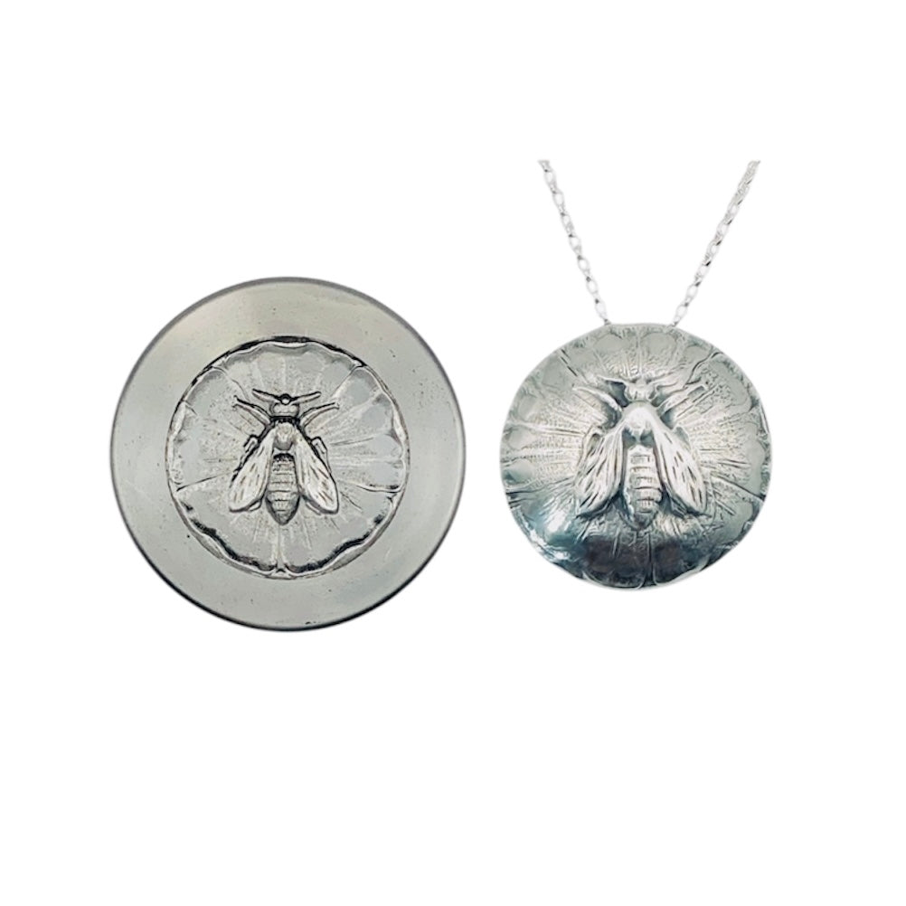 sterling silver pendant with a raised bee and textured and oxidised background subtly domed on a silver belcher chain necklace alongside the die that was used to make the handmade necklace in a sustainable way by Bottlebee in Nottingham who makes bespoke jewellery