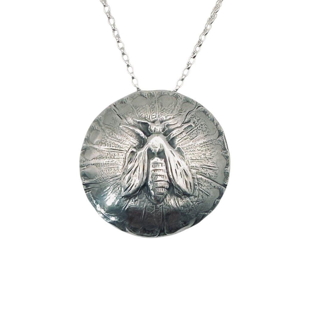 sterling silver pendant with a raised bee and textured and oxidised background subtly domed on a silver belcher chain necklace handmade in a sustainable way by Bottlebee in Nottingham who makes bespoke jewellery
