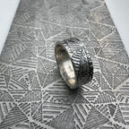 Solid sterling silver ring with textured geometric design on a textured metal geometric pattern surface handmade silverwedding ring nottingham