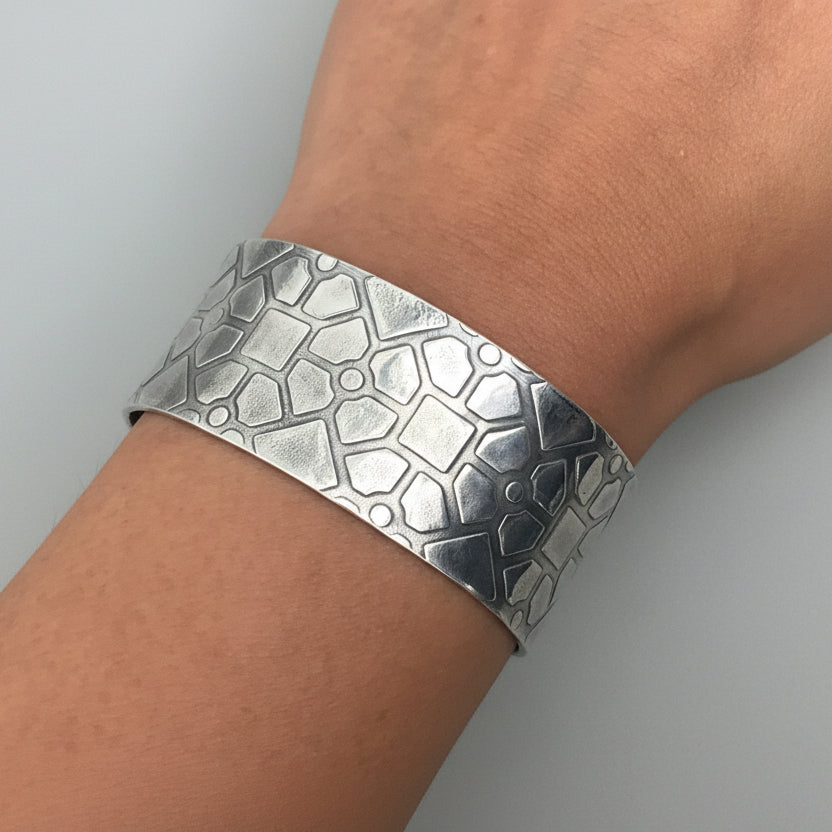 Silver jewellery cuff with geometric texture bracelet on a wrist handmade by Bottlebee in Nottingham