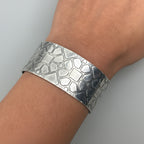 Silver jewellery cuff with geometric texture bracelet on a wrist handmade by Bottlebee in Nottingham