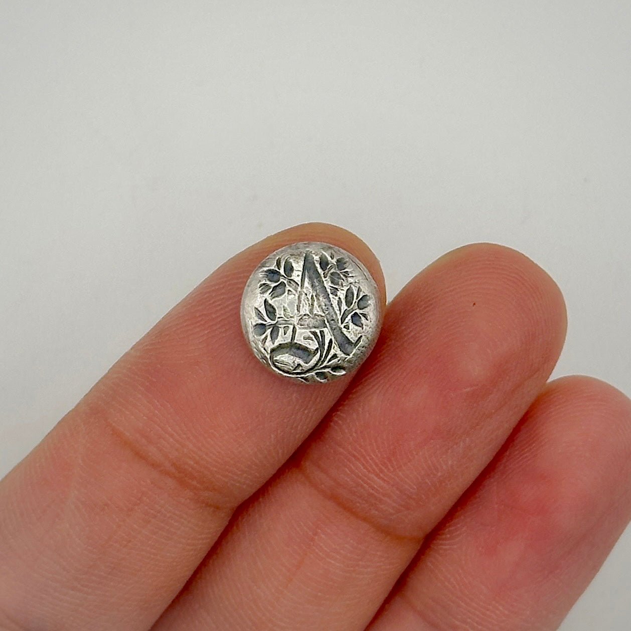 Silver personalised jewellery made in nottingham shown on a finger against a white background made in Nottingham with initial a