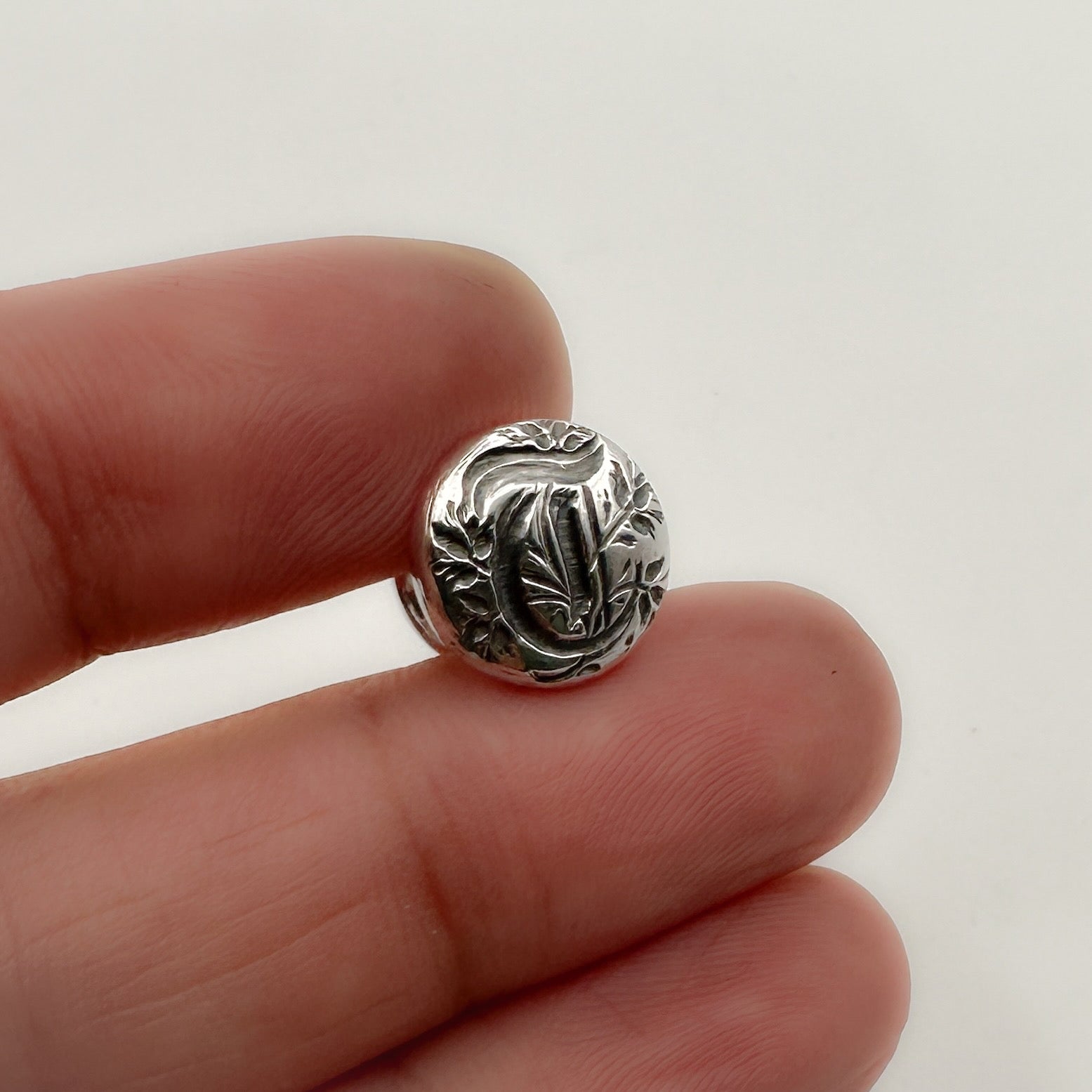 Silver personalised initial cufflinks jewellery shown on a finger against a white background made in Nottingham