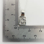 Silver pendant with a geometric design on a ruler for scale, handmade in Nottingham by Bottlebee
