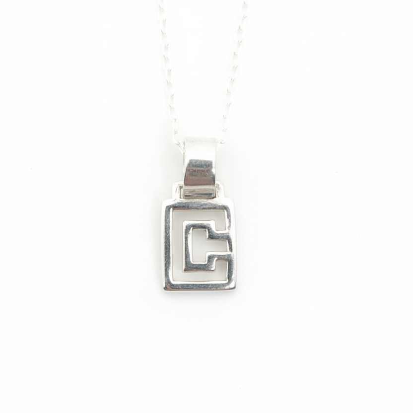 Silver geometric pendant on a white background with a thin delicate chain 