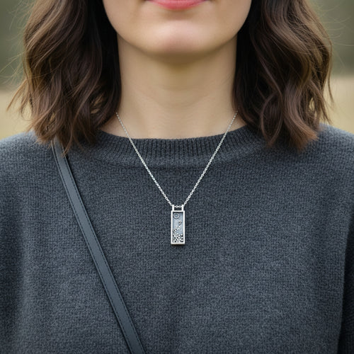 Person wearing a silver necklace with a rectangular pendant and a silver belcher chain. Necklace made by in a sustainable way by Bottlebee in Nottingham