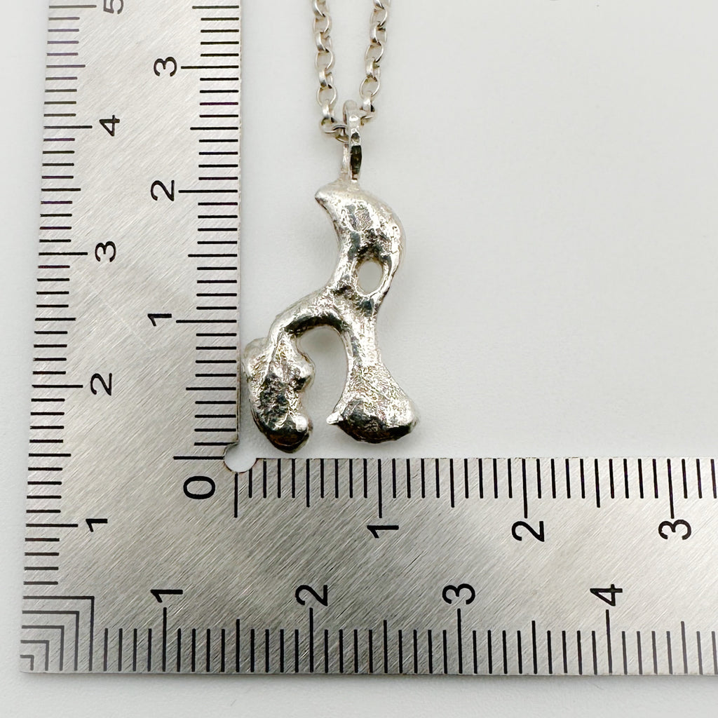 Silver pendant on a chain which has been sustainable made with recycled sterling silver next to a ruler for scale. Handmade bespoke jewellery in Nottingham