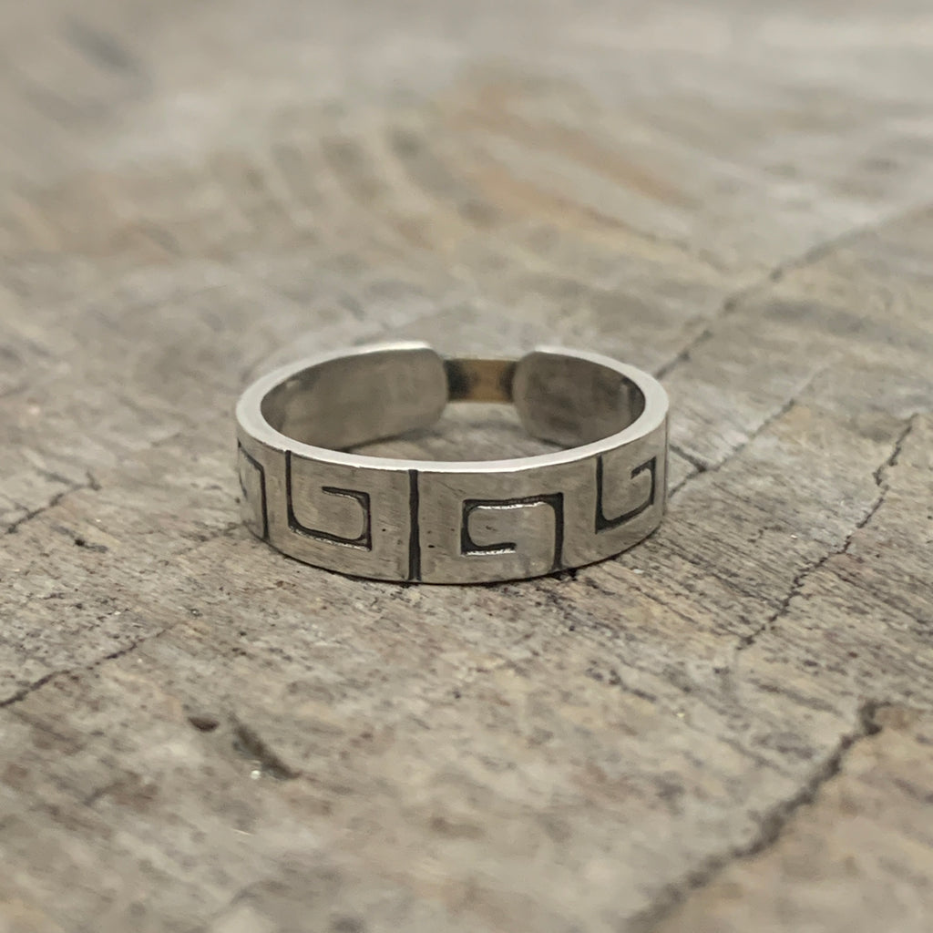 a silver and gold ring with Bottlebee stamped inside. The ring has a greek style pattern on teh outside