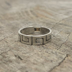 a silver and gold ring with Bottlebee stamped inside. The ring has a greek style pattern on teh outside