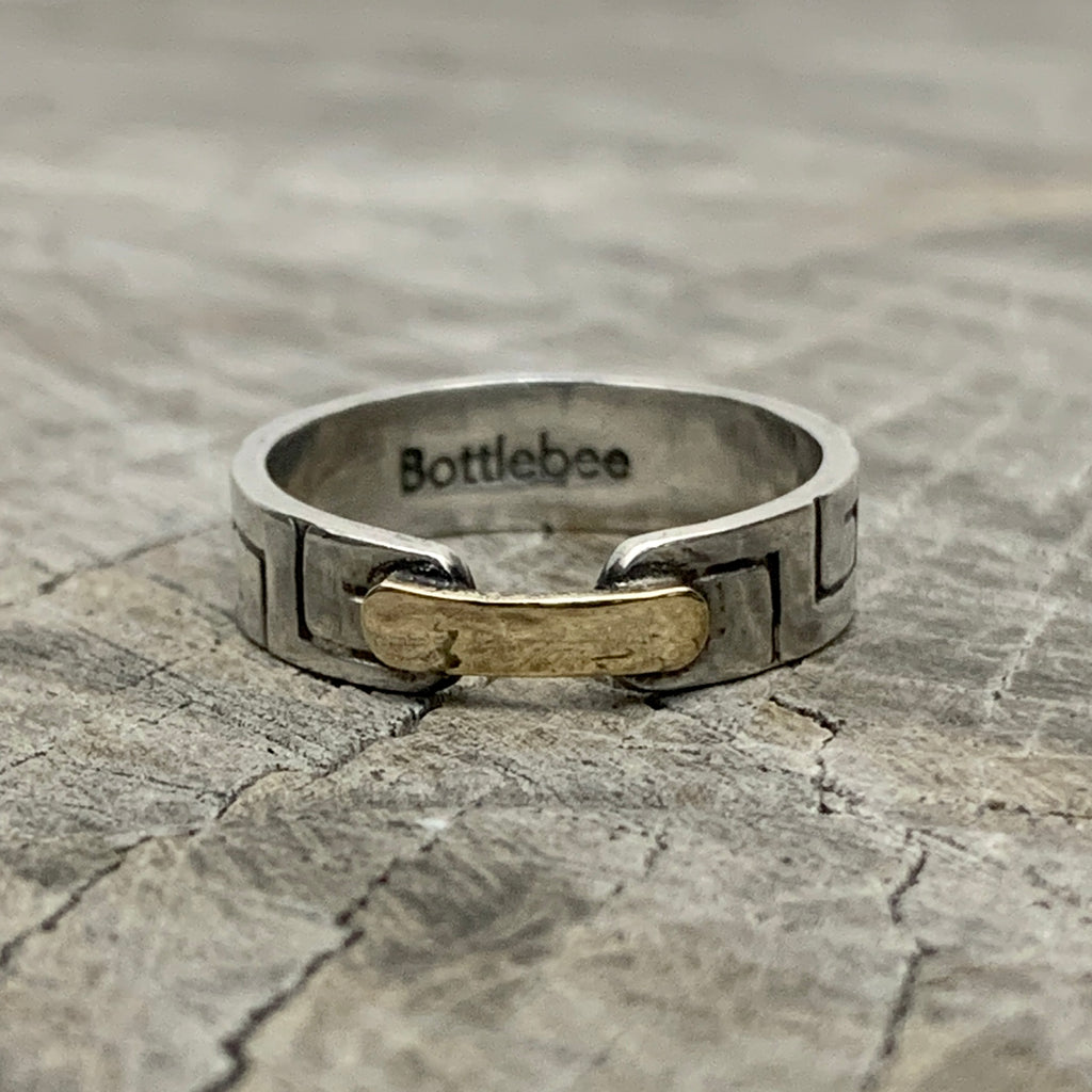 a silver and gold ring with Bottlebee stamped inside. The ring has a greek style pattern