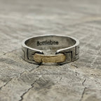 a silver and gold ring with Bottlebee stamped inside. The ring has a greek style pattern