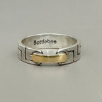 a silver and gold ring with Bottlebee stamped inside. The ring has a greek style pattern