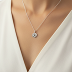 Woman wearing a white top and a sterling 925 silver necklace with a round pendant with a raised oxidised frog. The jewellery has been sustainably handmade by Bottlebee who is based in Nottingham