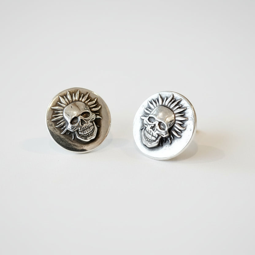 Pair of handmade silver skull earrings on a white background made by small business called Bottlebee in Nottingham